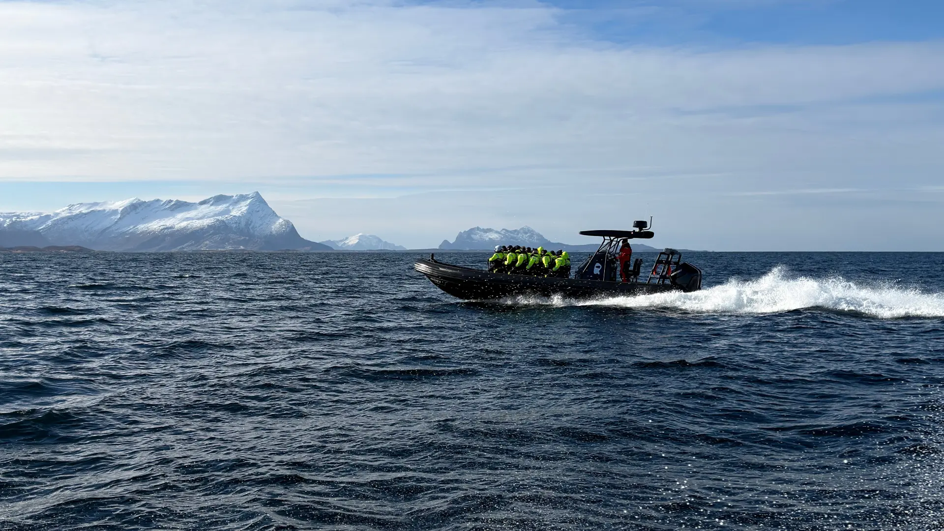 RIB boat with guests in flotation suits in the winter archipelago outside Bodø